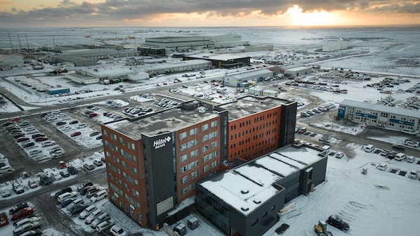 A hotel with a modern architectural design, featuring a prominent red building with a sign that reads "Hotel Aurora."