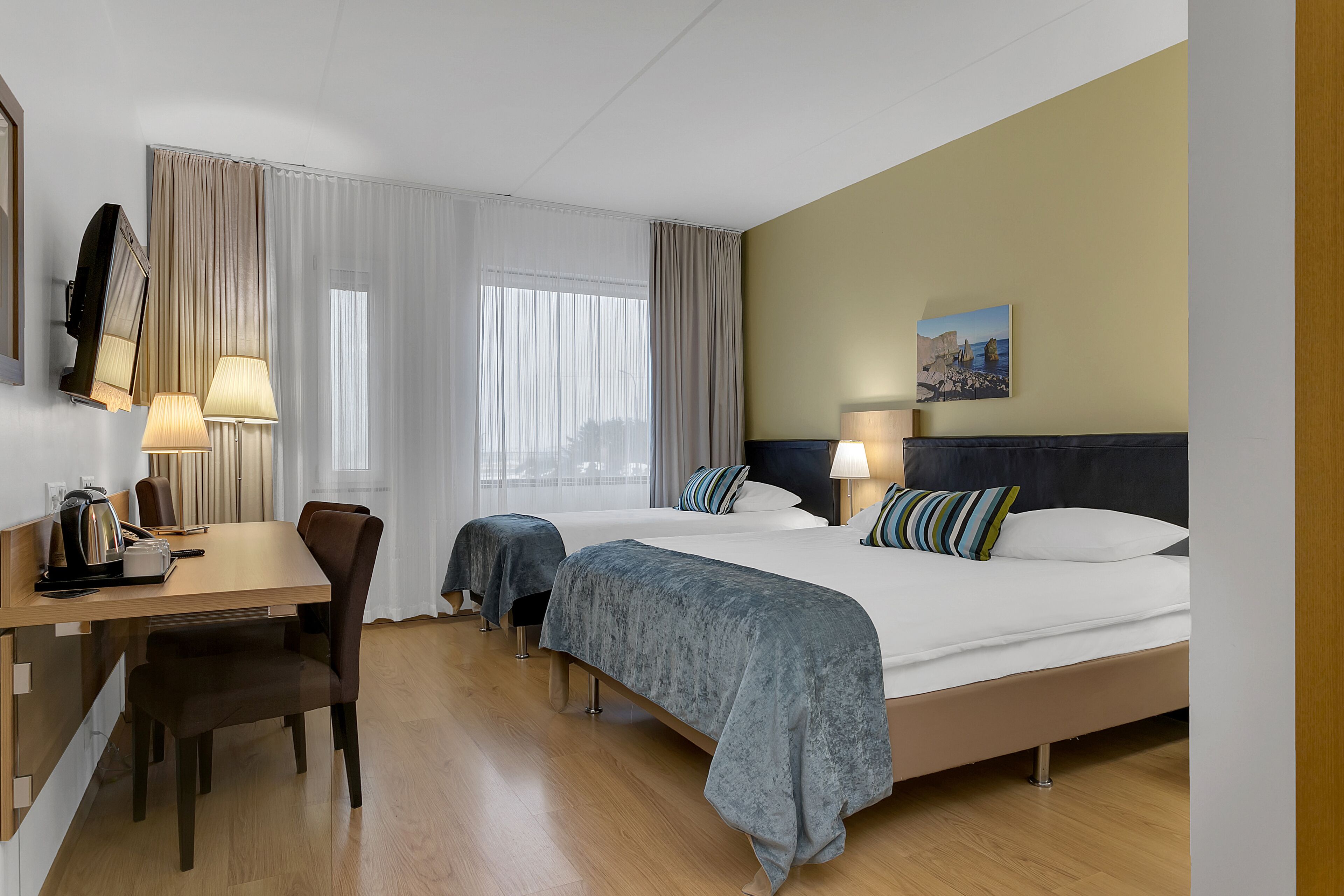 A hotel room with a bed, bedside tables, a desk, and a chair.