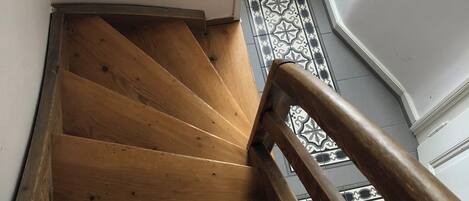 A wooden staircase with a patterned floor and a handrail.