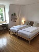 Un dormitorio con dos camas individuales, un escritorio, una silla y una ventana.
