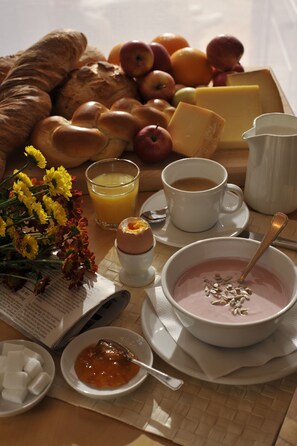 A breakfast tray with croissants, fruits, cheese, coffee, and a bowl of soup. - The Bed and Breakfast (Lucerne)