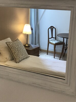 A bedroom with a bed, a nightstand, a lamp, a chair, and a table.