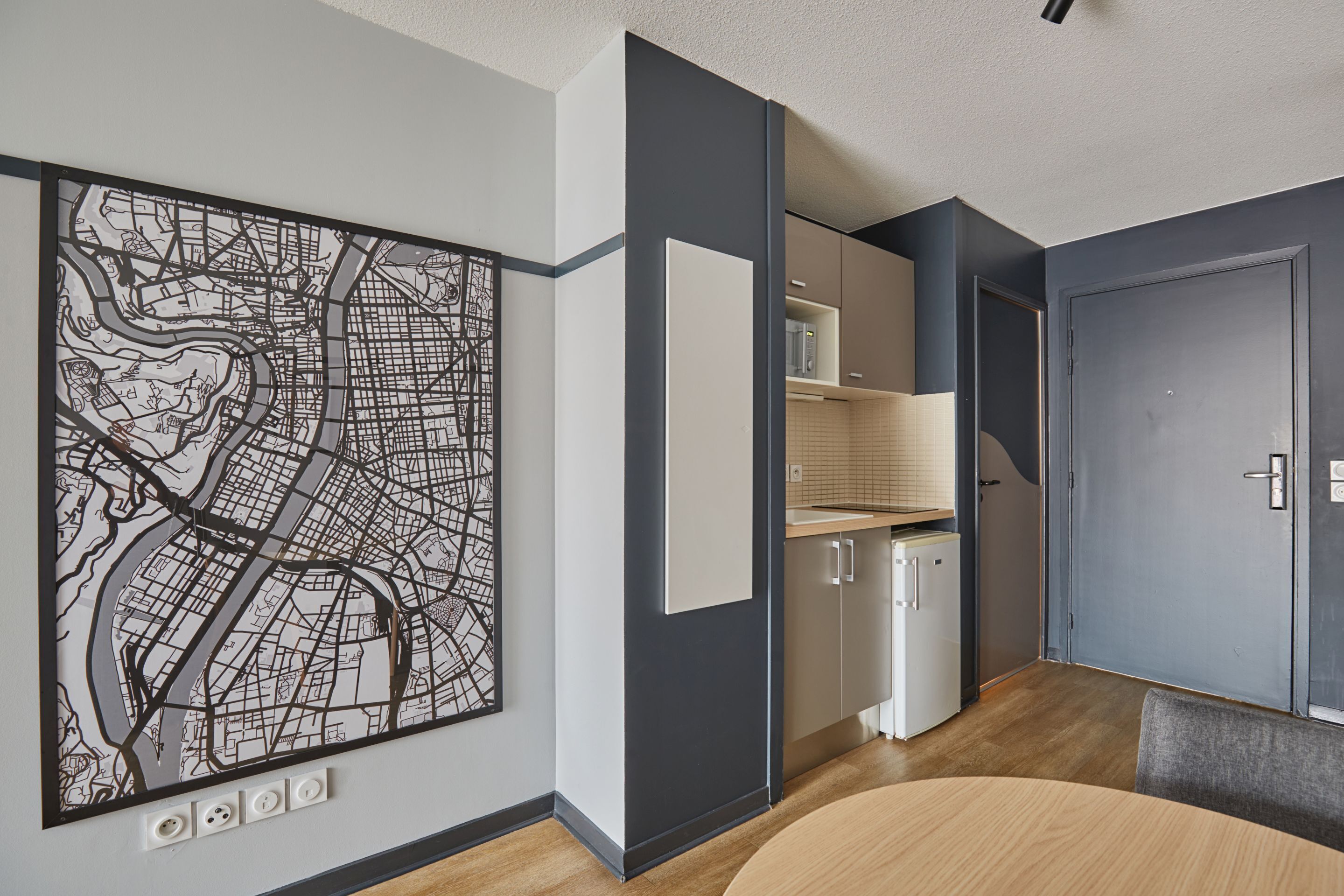 A modern kitchen with a large map artwork, built-in cabinets, and a dining area with a round table.