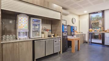 A modern kitchen area with a coffee machine, a refrigerator, and a small table with a cup and saucer.