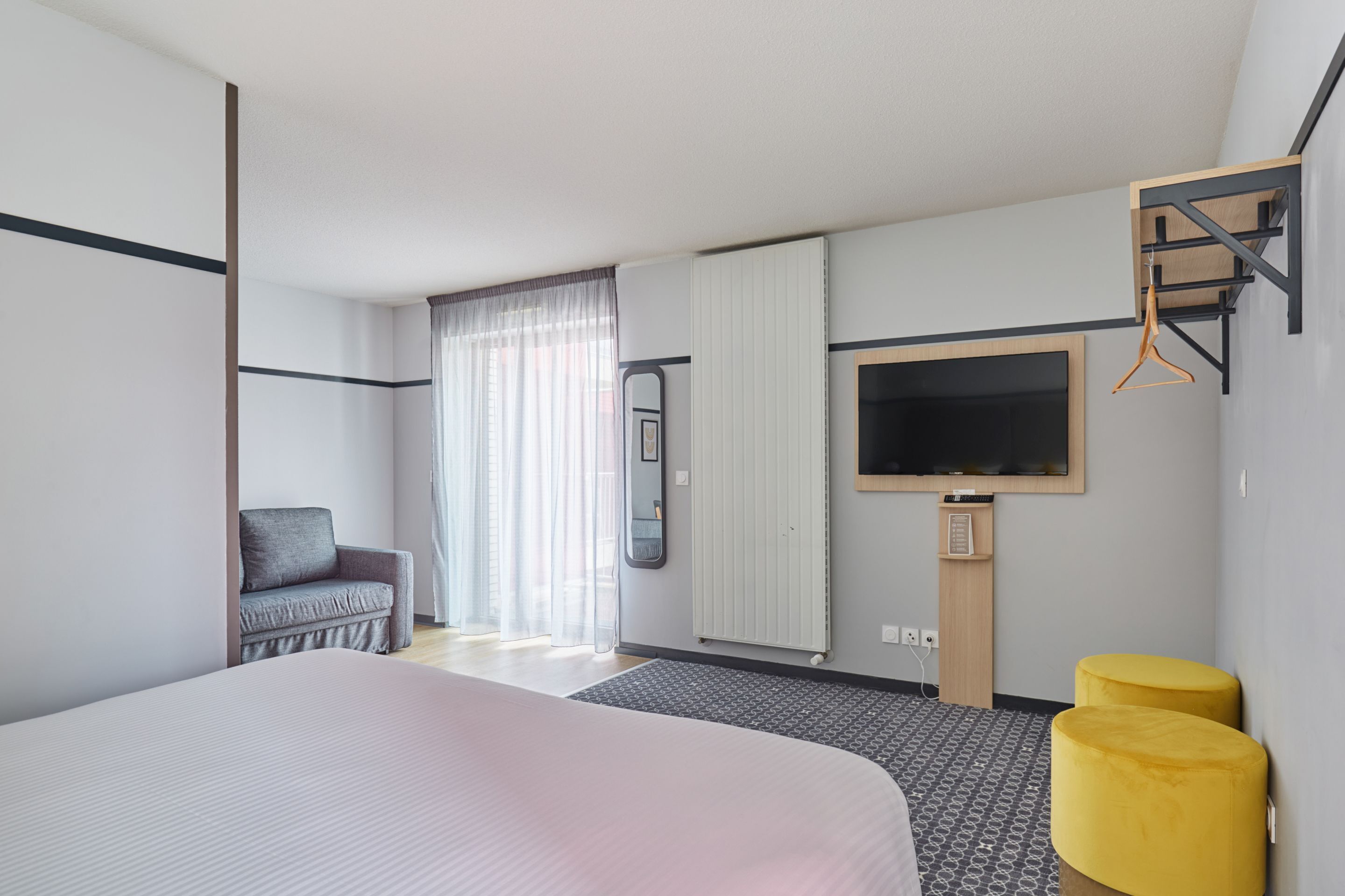 Een moderne hotelkamer met een groot bed, een bank, een televisie en een tafeltje.