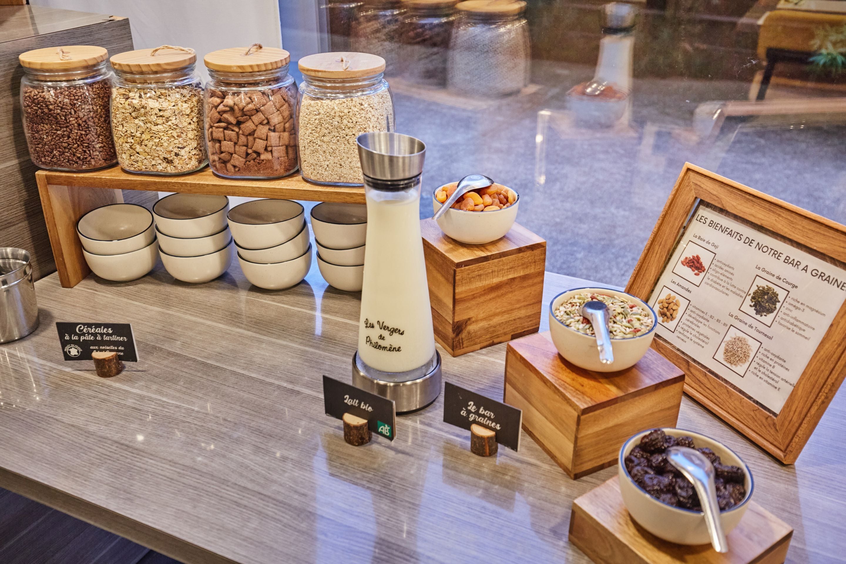A breakfast buffet with various cereals, grains, and a milk dispenser.