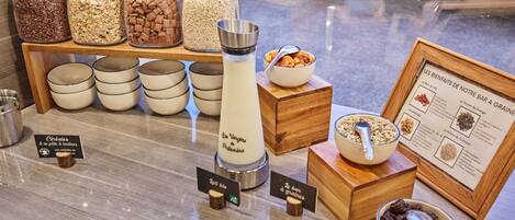 A breakfast buffet with various cereals, grains, and a milk dispenser.