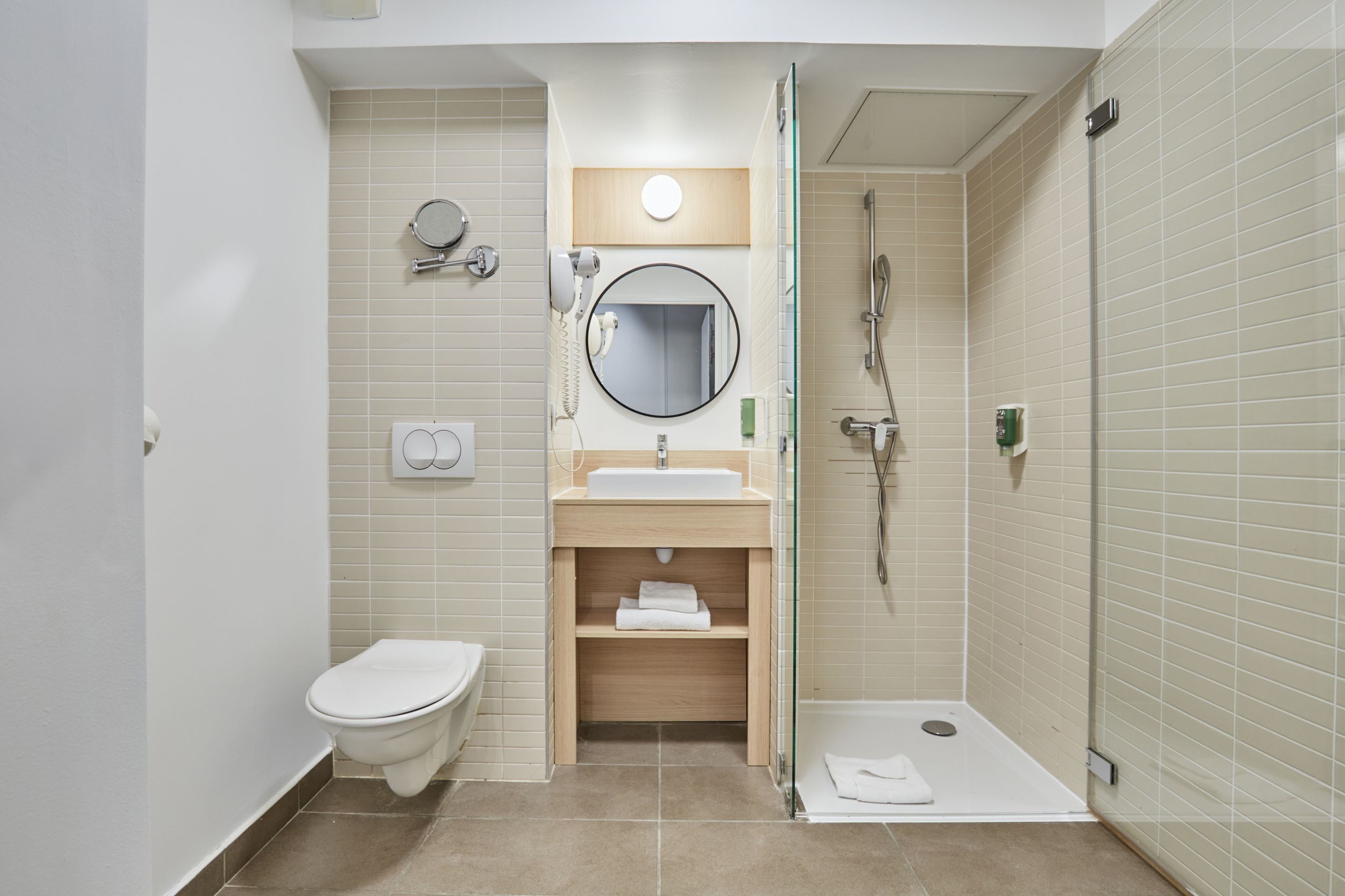 A modern bathroom with a toilet, sink, mirror, and shower.