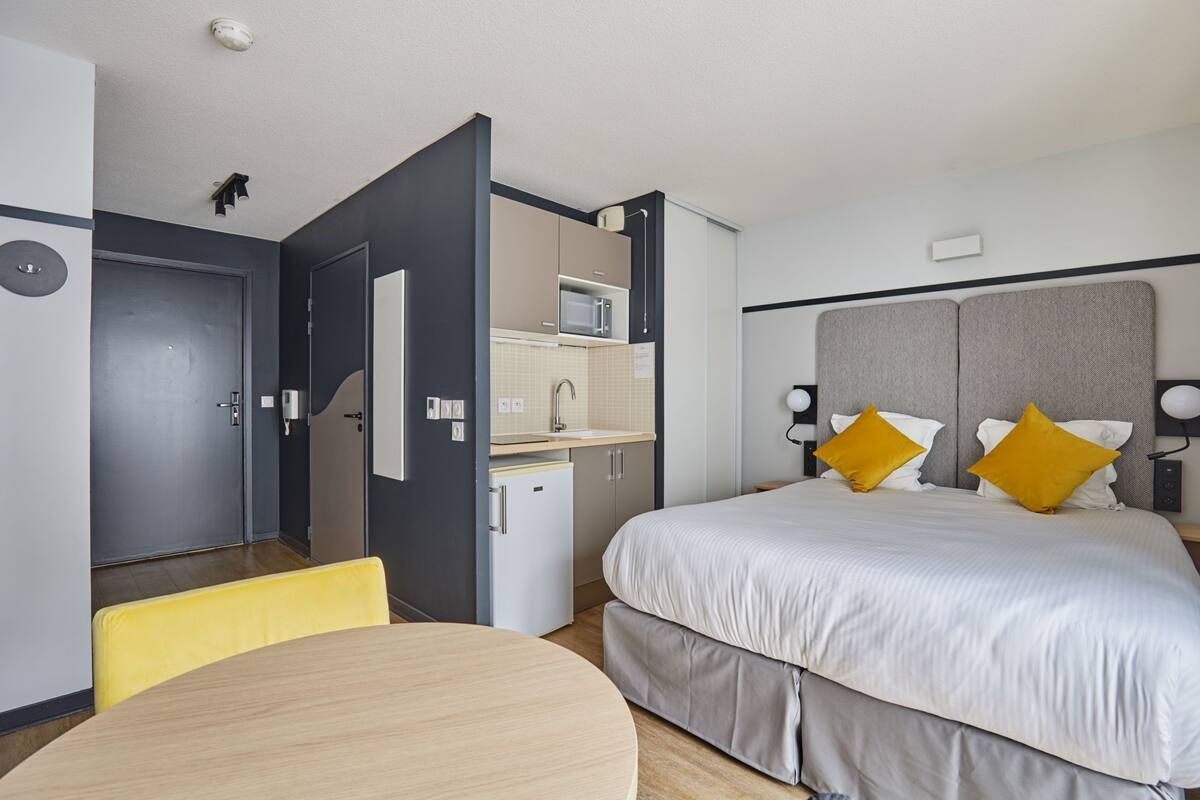 Une chambre d’hôtel comprenant un lit, une petite kitchenette, une table à manger et une salle de bain séparée.