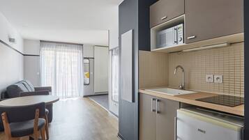 Una cucina moderna con forno a microonde, lavello e frigorifero. C'è una zona pranzo con tavolo e sedie.