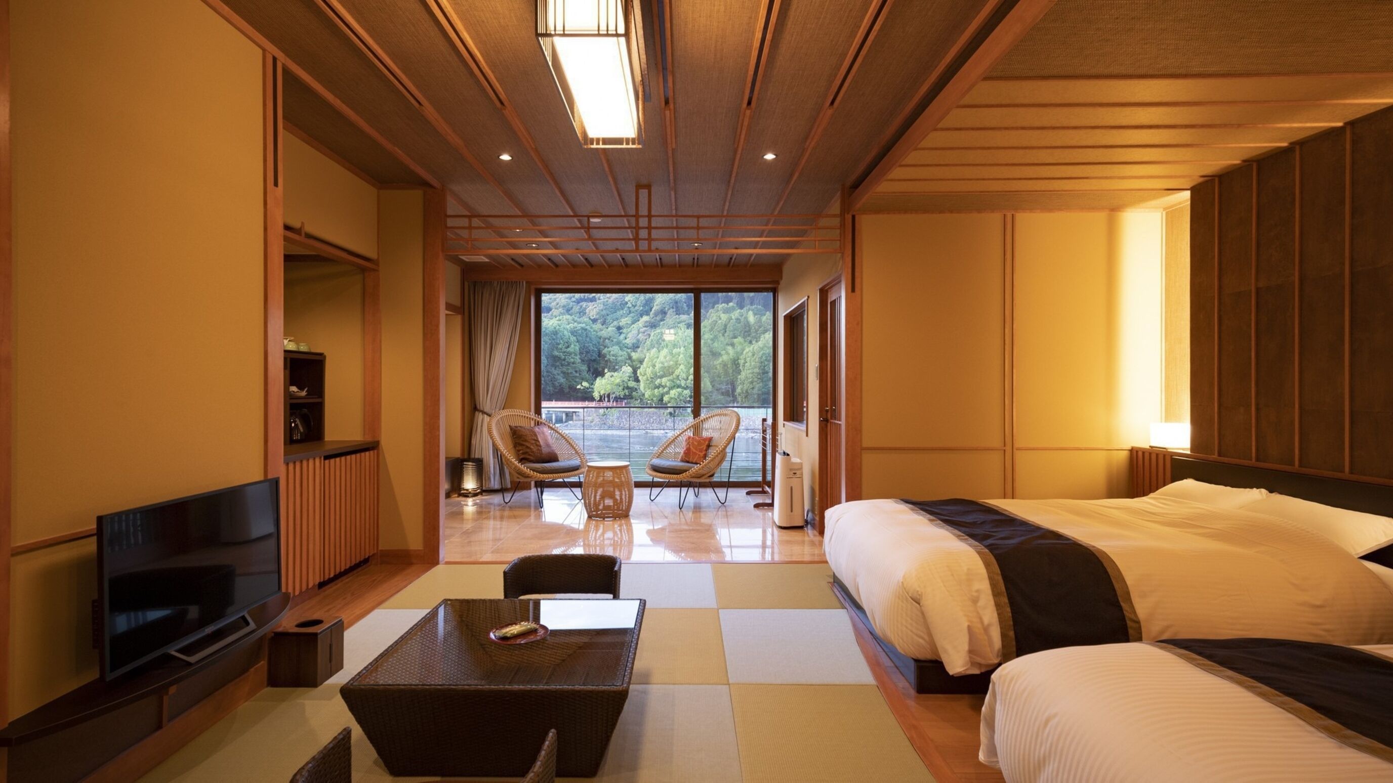 A hotel room with a large bed, a TV, a seating area with chairs, and a view of the outdoors.