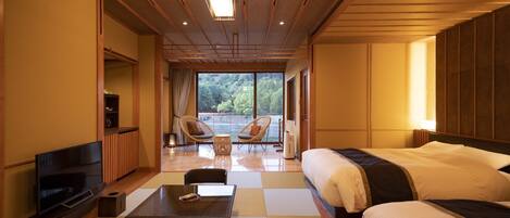 A hotel room with a large bed, a TV, a seating area with chairs, and a view of the outdoors.