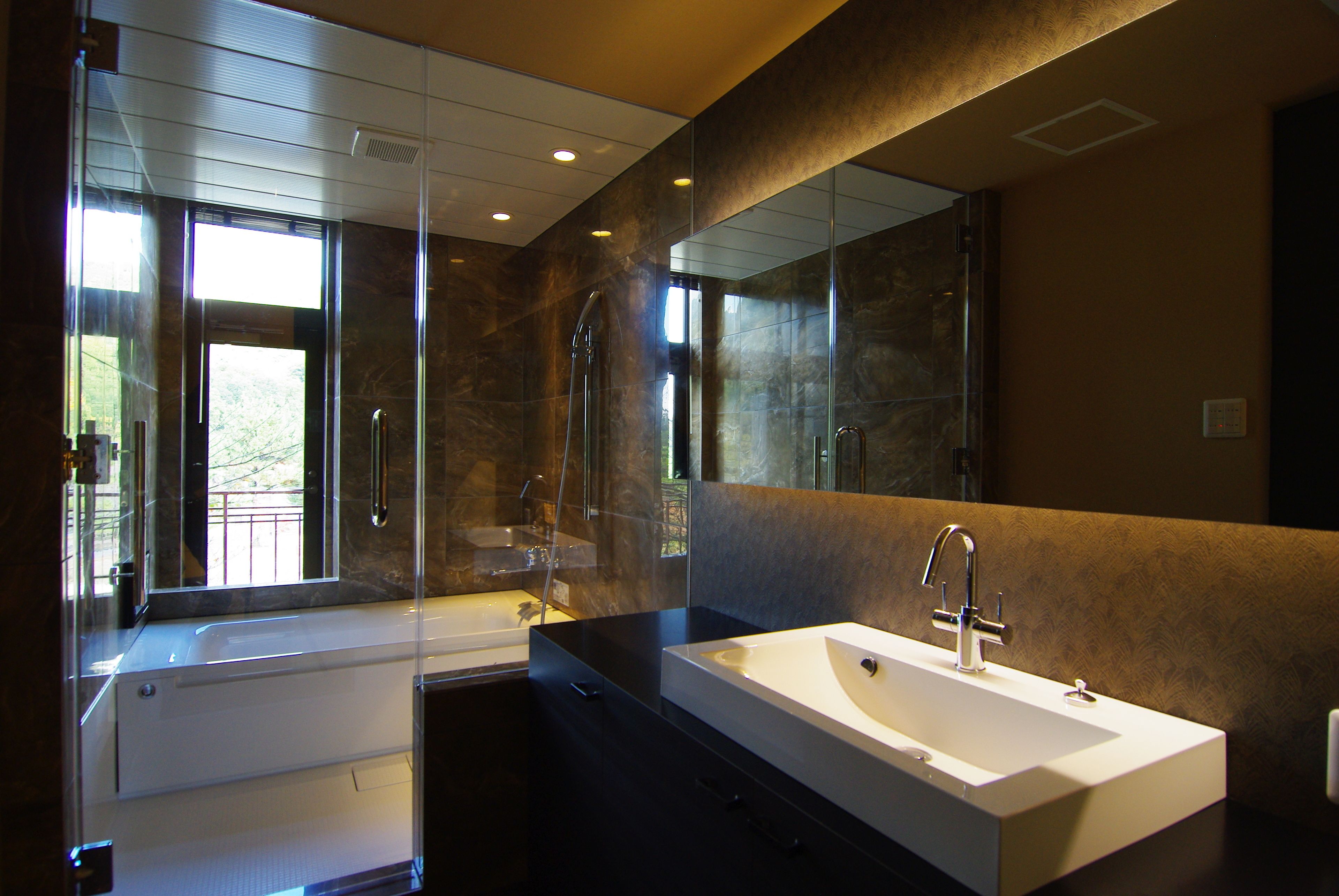 A modern bathroom with a large mirror, a bathtub, and a sink.