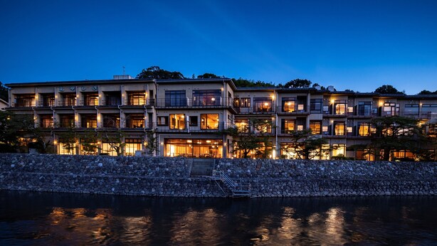A multi-story hotel with a stone facade, multiple balconies, and a waterfront view.