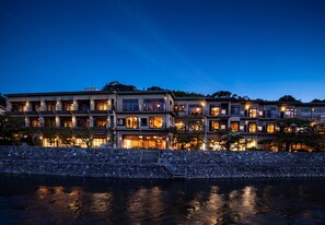 A multi-story hotel with a stone facade, multiple balconies, and a waterfront view. - Kyoto Uji Hanayashiki Ukifune-en (Uji)