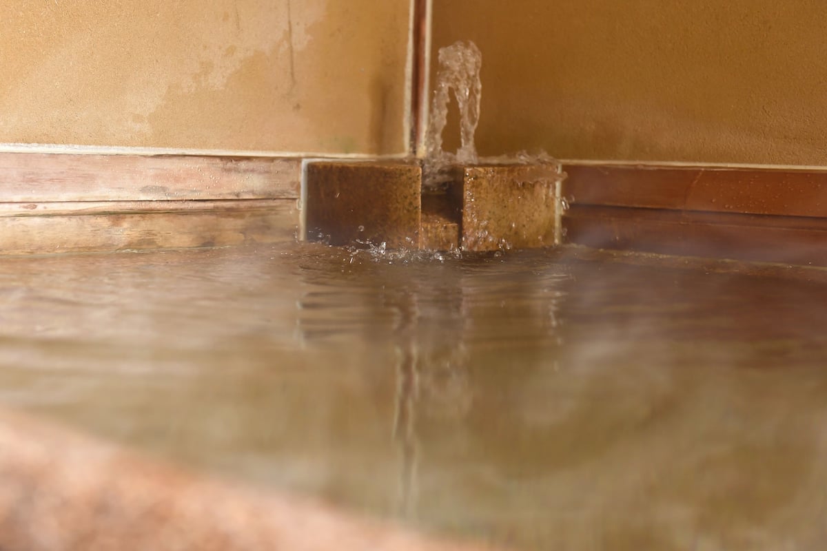 A close-up of a water feature with a clear stream flowing from a spout into a shallow pool.