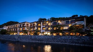 A multi-story hotel with balconies and large windows, located near a body of water.