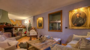 Una sala acogedora con chimenea, un árbol de Navidad y varios retratos enmarcados en la pared.