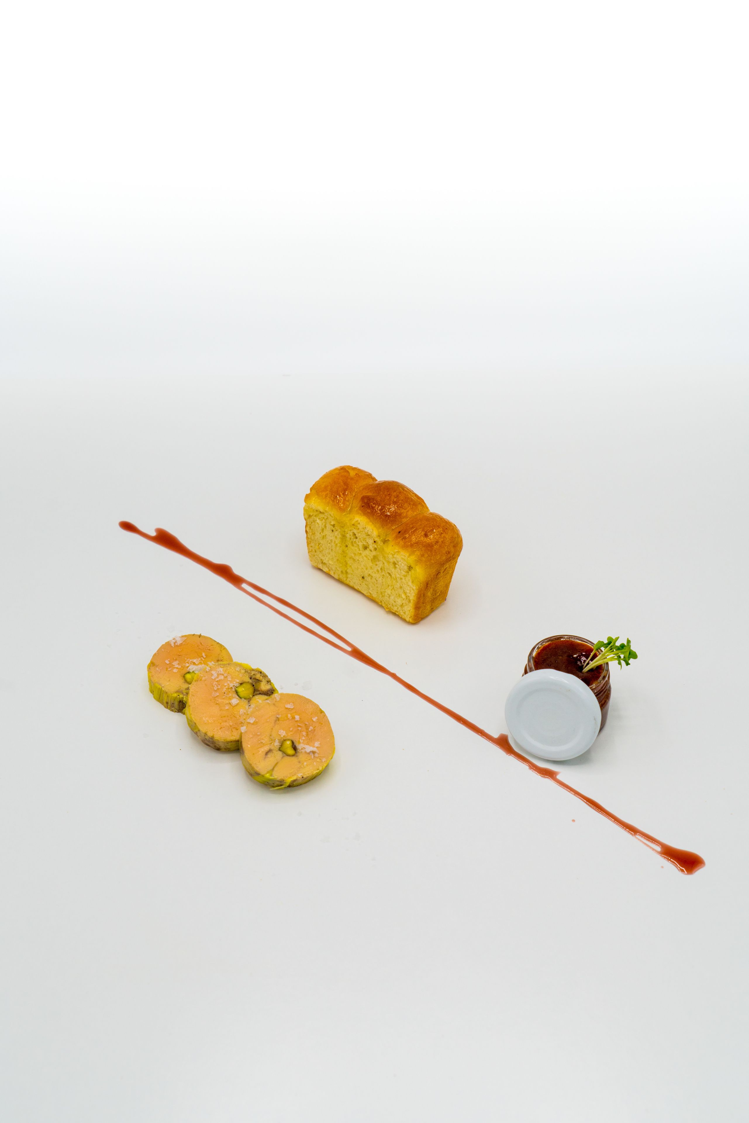 Ein Dessertteller mit Kuchen, drei runden Gebäcken und einem kleinen Saucenglas.