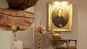 Una habitación rústica con una silla de madera, un retrato enmarcado y una planta decorativa.