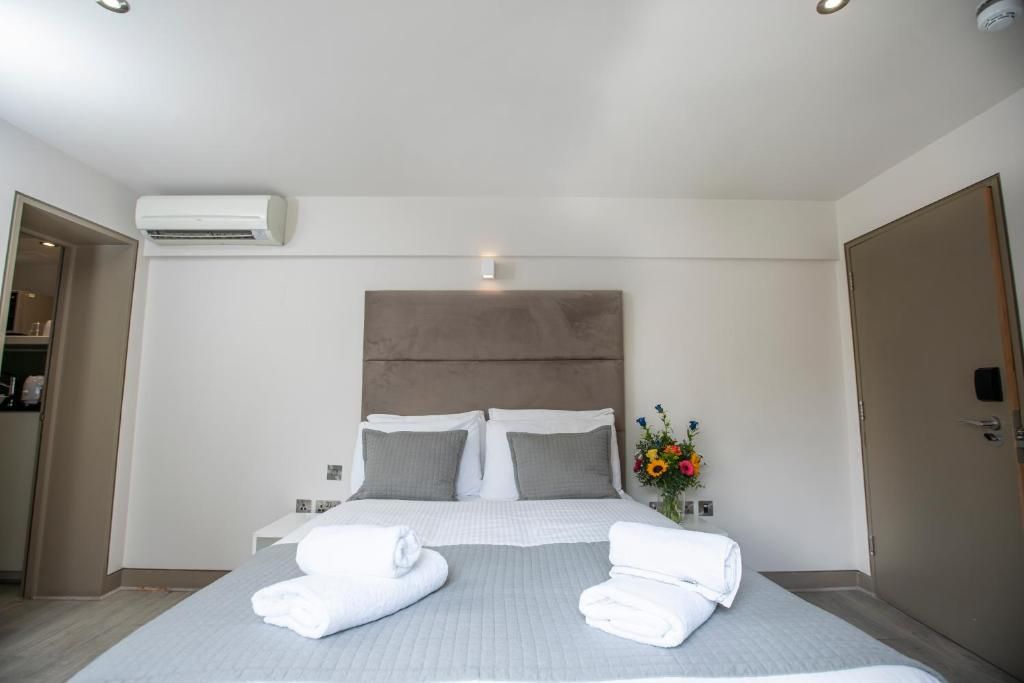 Ein Hotelzimmer mit einem Bett, einem Nachttisch, einer Wand-Klimaanlage und einer Tür.