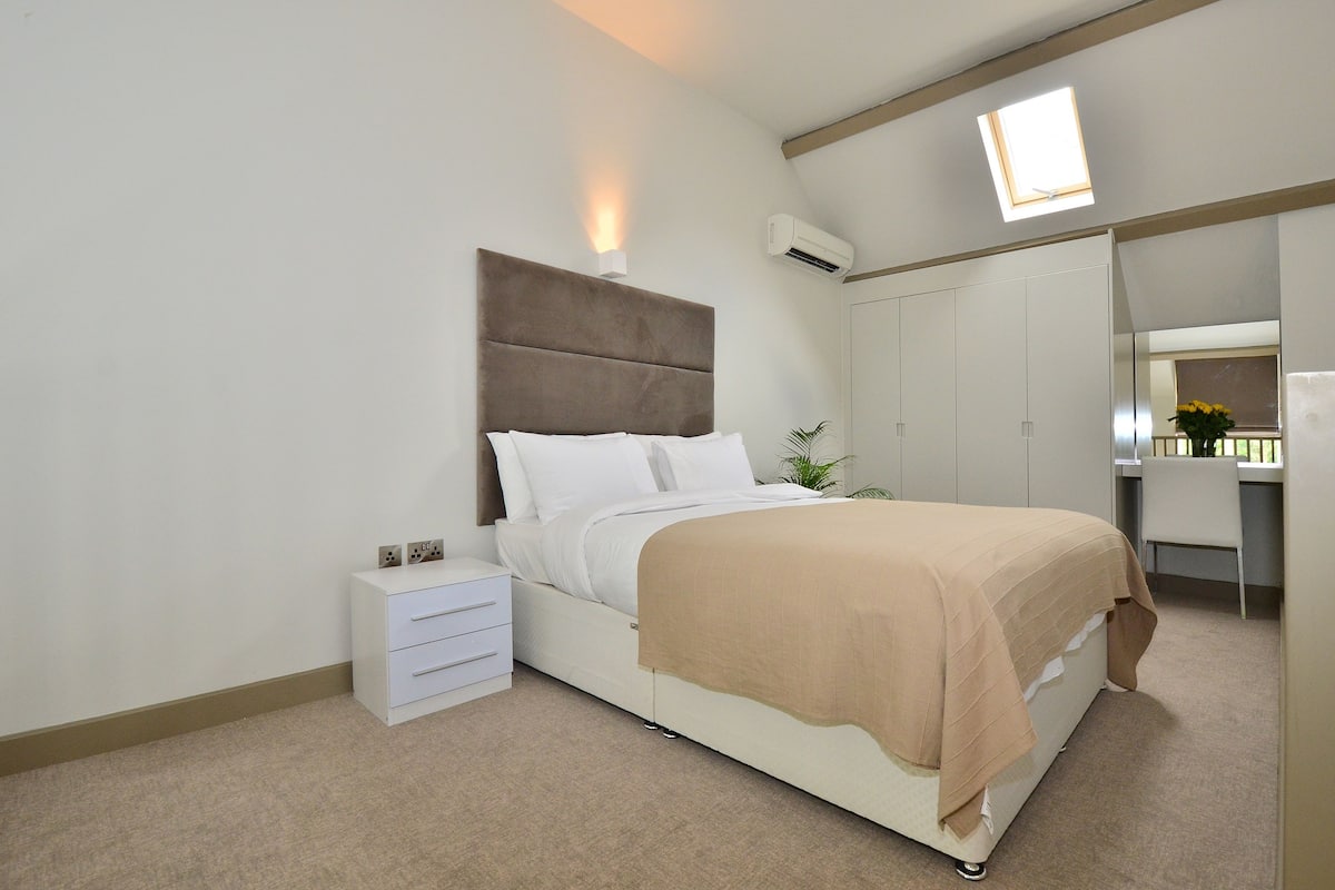 Ein Schlafzimmer mit Bett, Nachttisch, Kleiderschrank und einem kleinen Fenster.