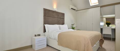 A bedroom with a bed, bedside table, wardrobe, and a small window.
