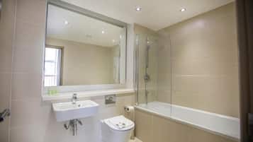 A bathroom with a sink, toilet, and a glass-enclosed shower area.