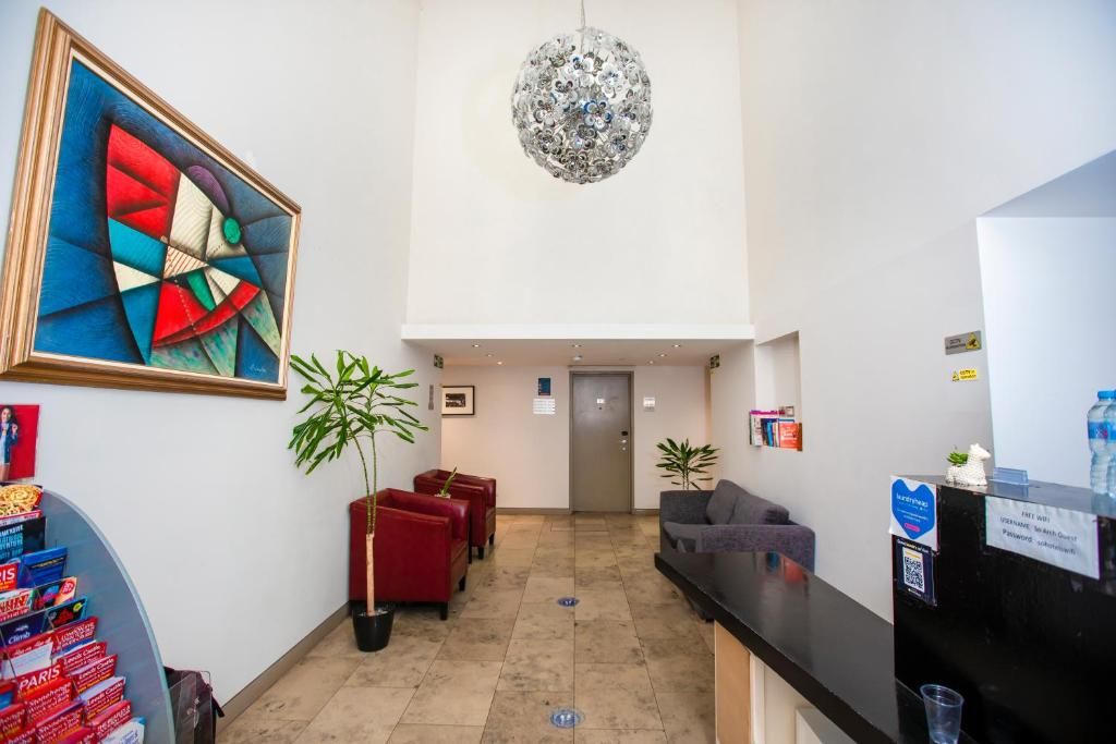 A hotel lobby with a reception desk, seating area, and a large abstract painting.
