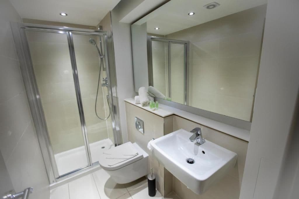 A modern bathroom with a glass-enclosed shower, a toilet, and a sink.
