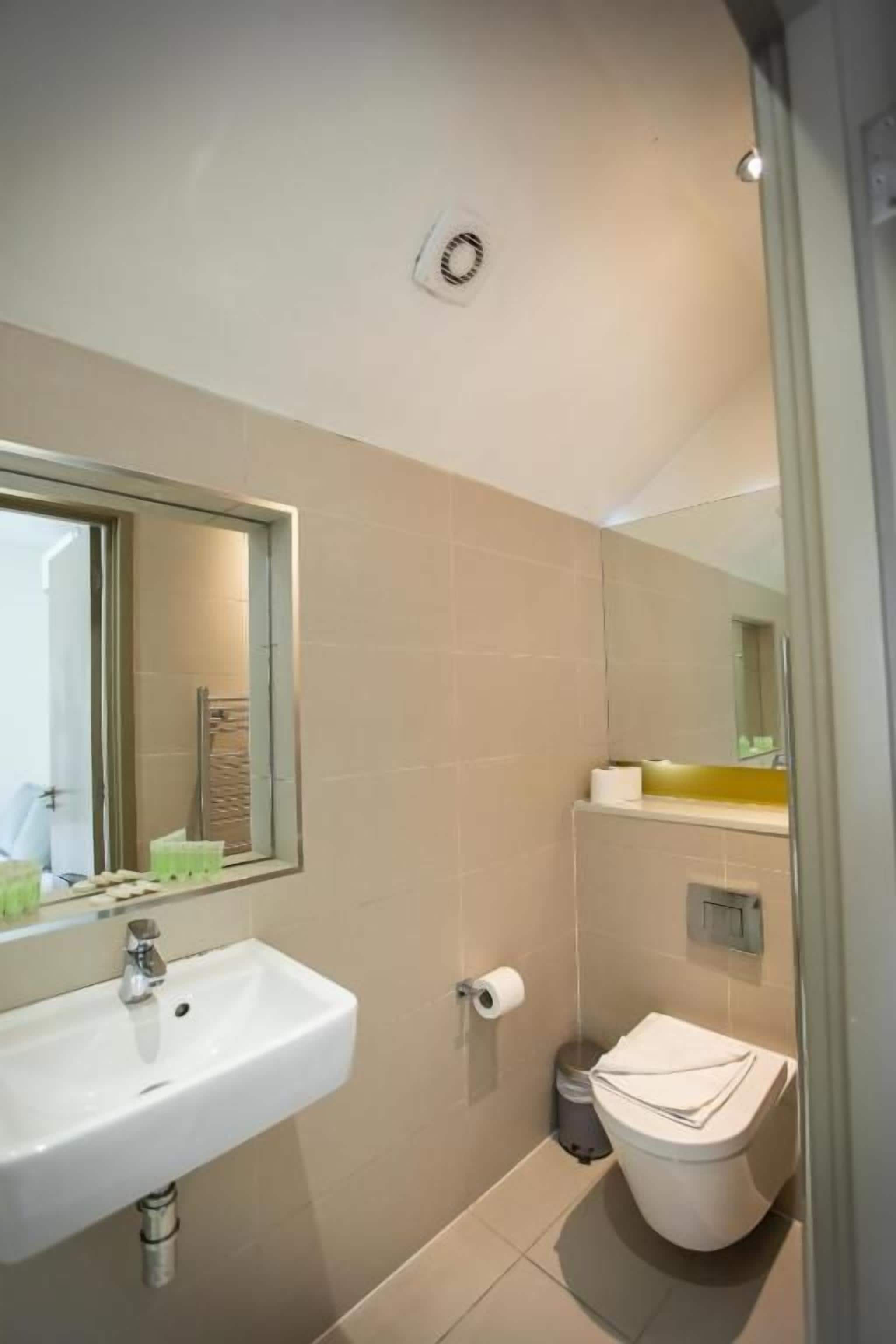 A bathroom with a sink, toilet, and mirror.