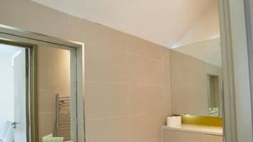 A bathroom with a sink, toilet, and mirror.