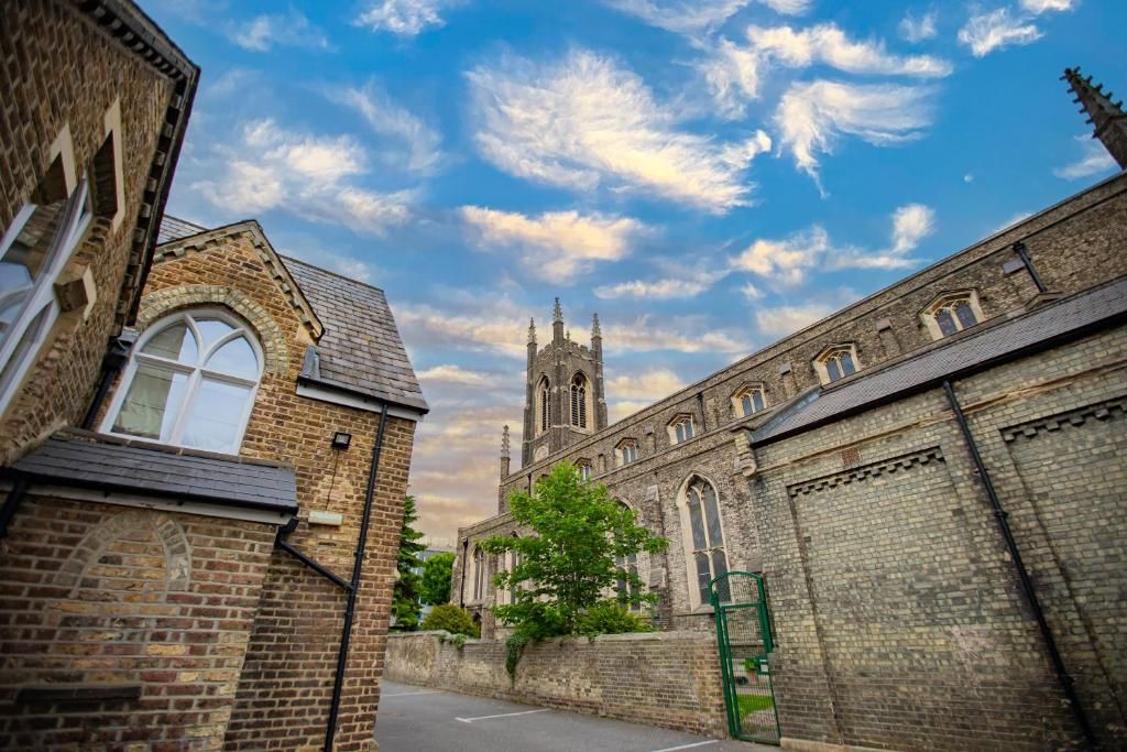 A historic building with a prominent tower and arched windows, surrounded by brick walls and a clear sky.