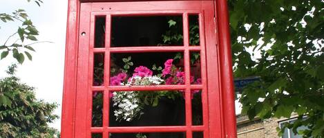 A red telephone booth with floral decorations.