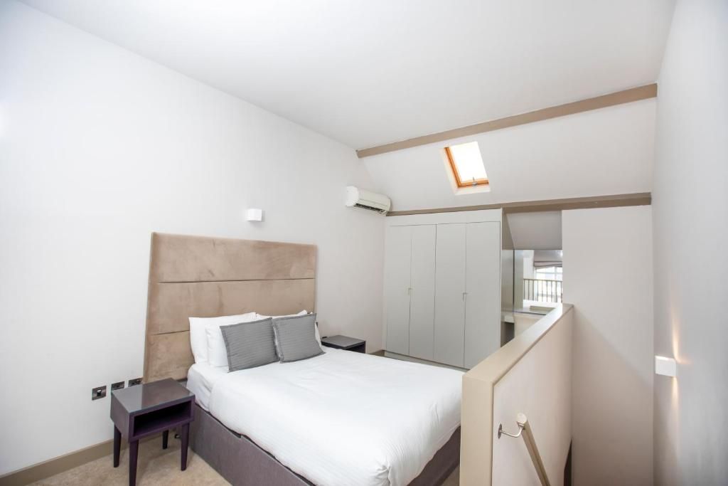 A bedroom with a bed, bedside tables, a wardrobe, and a window.