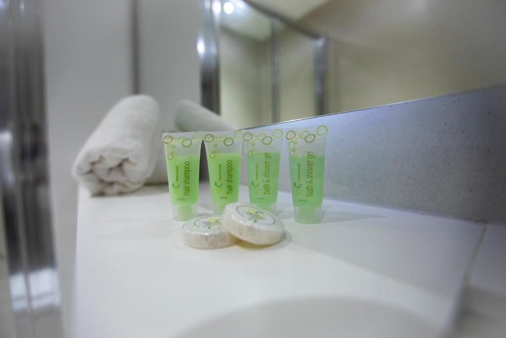 Une salle de bain avec un miroir, une serviette et trois flacons de gel pour les cheveux et le corps.