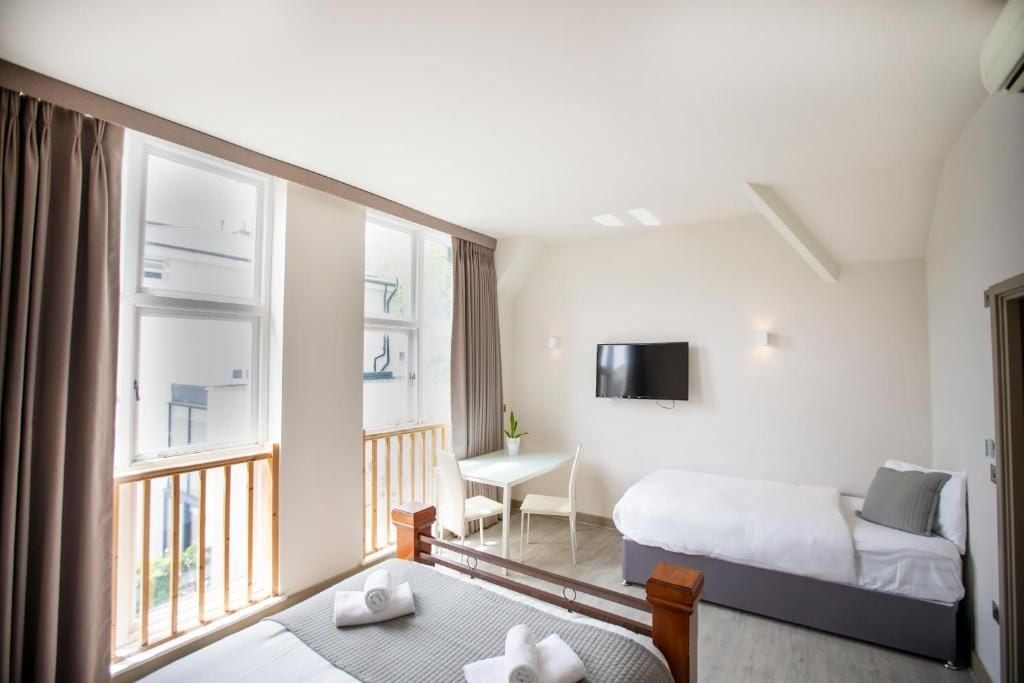 A hotel room with a bed, a desk, a chair, a TV, and a balcony.