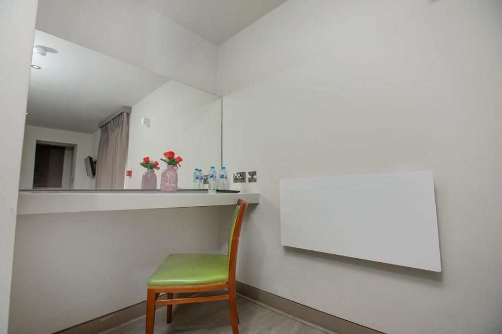 A bathroom with a mirror, a chair, a shelf with toiletries, and a whiteboard.