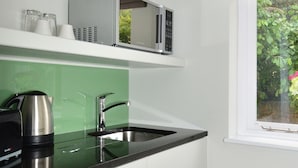 A modern kitchen with a stainless steel kettle, a microwave, and a sink. - Arch hotel (London)