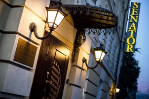 Entrada de un edificio con un letrero que dice "SENATOR APARTMENTS" y una puerta de madera oscura.