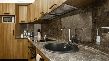 Una cocina moderna con armarios de madera, un lavamanos negro y un salpicadero de mármol.