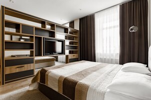Habitación de hotel moderna con una cama grande, televisión integrada y amplios estantes para almacenamiento.