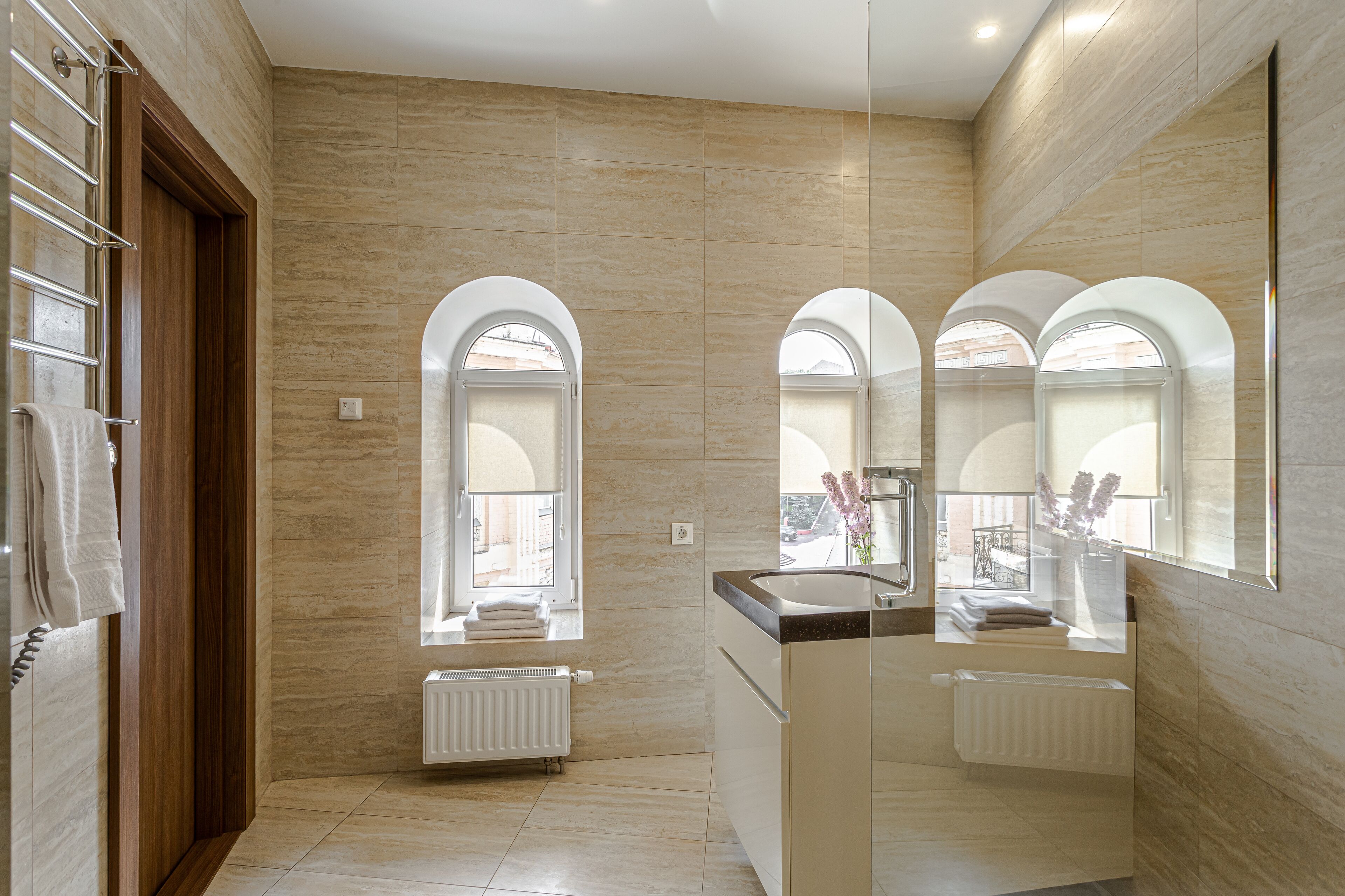 A modern bathroom with a large mirror, a sink, and a shower area.