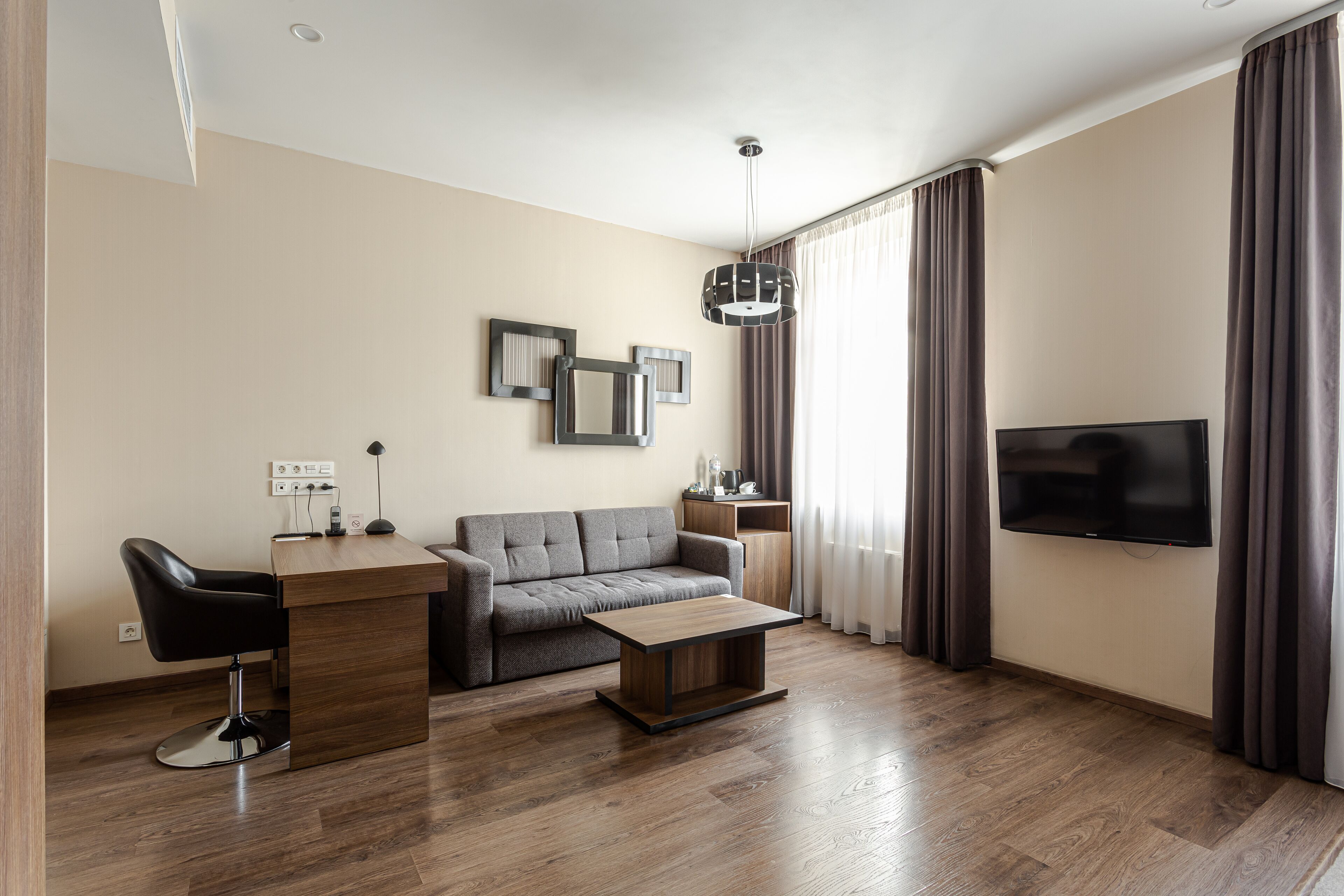 A modern living room with a sofa, a coffee table, a TV, and a desk with a chair.