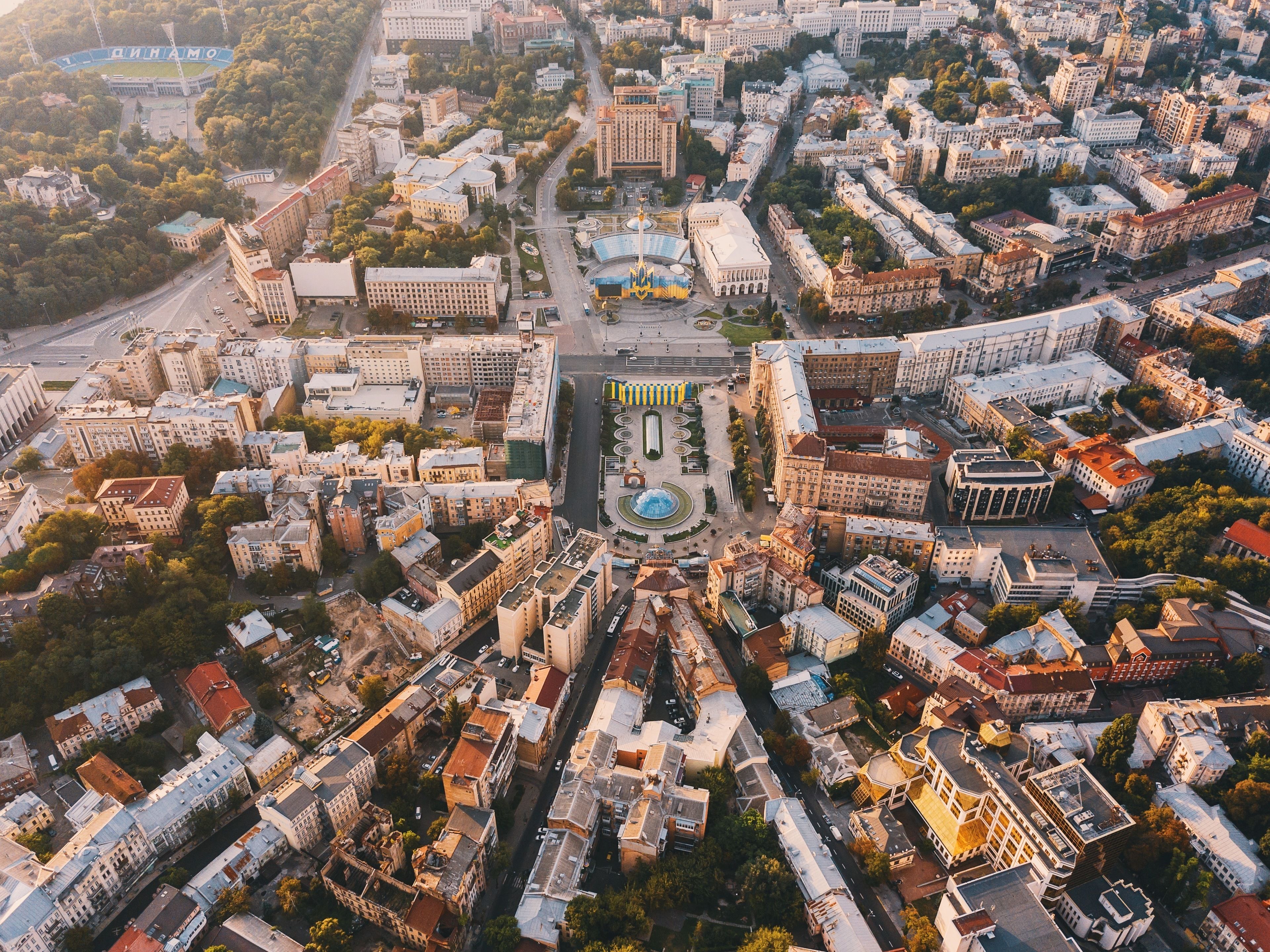 Eine Vogelperspektive auf eine Stadtlandschaft mit einem markanten, zentralen Platz, umgeben von verschiedenen Gebäuden und Straßen.