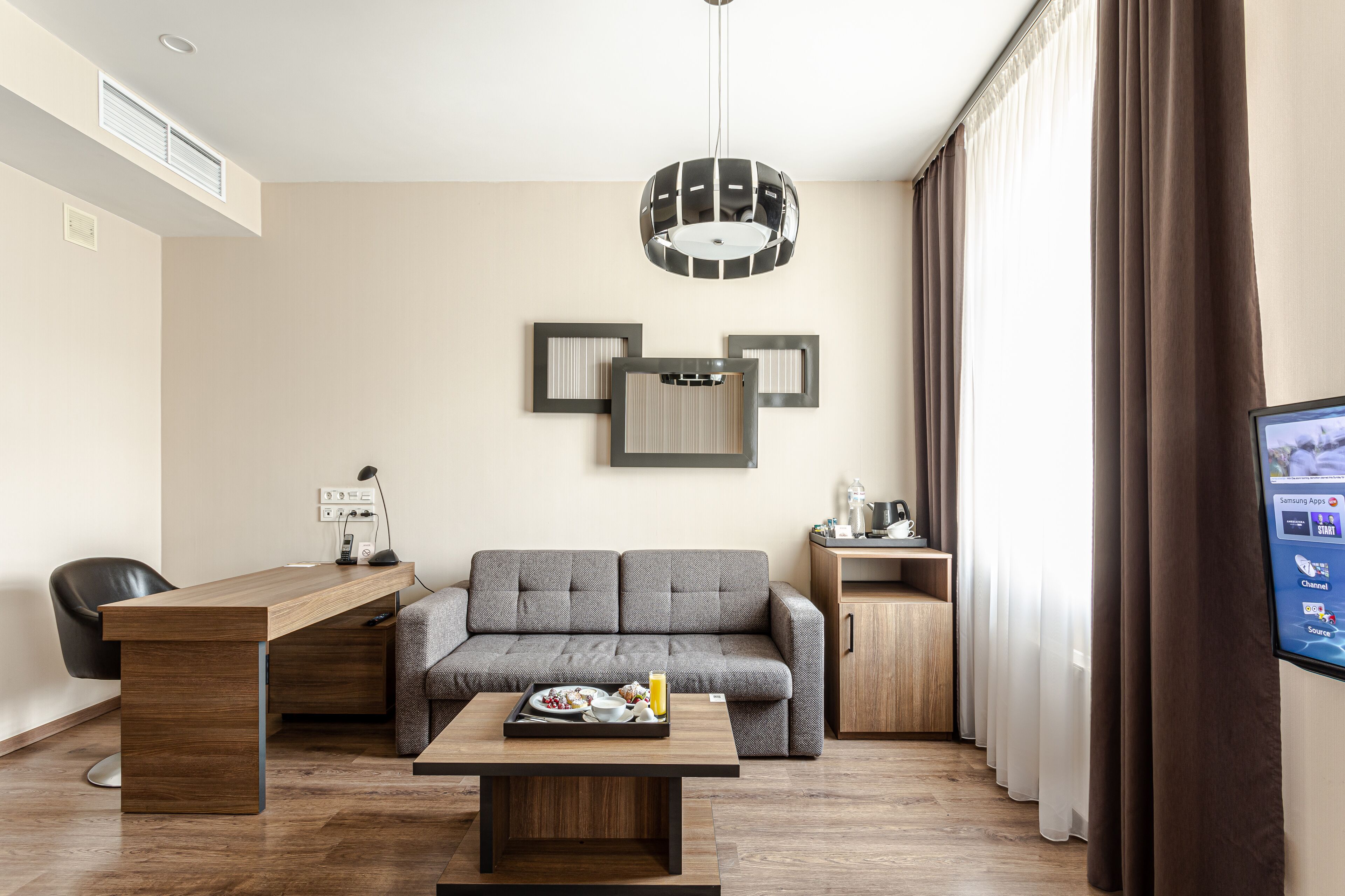 Una sala de estar moderna con un sofá, una mesa de centro de madera, un escritorio y un televisor.