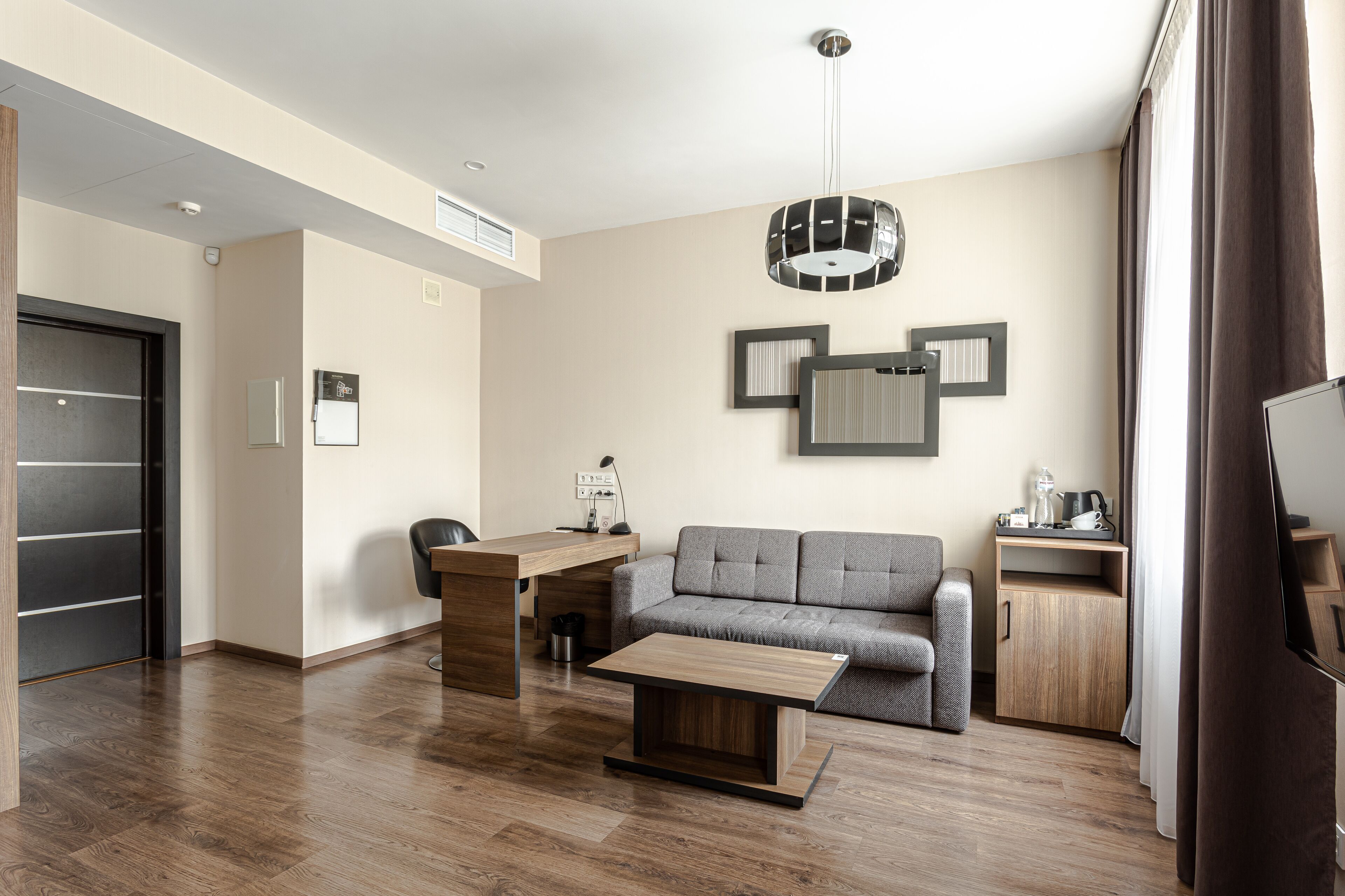 A modern living room with a sofa, a coffee table, a desk, and a TV.