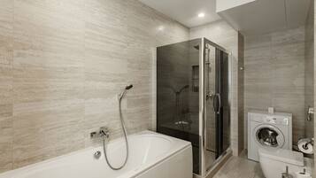 Un baño moderno con bañera, cabina de ducha de vidrio y lavadora integrada.