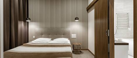 A modern bedroom with a large bed, a bedside table, a wardrobe, and a bathroom visible through an open door.
