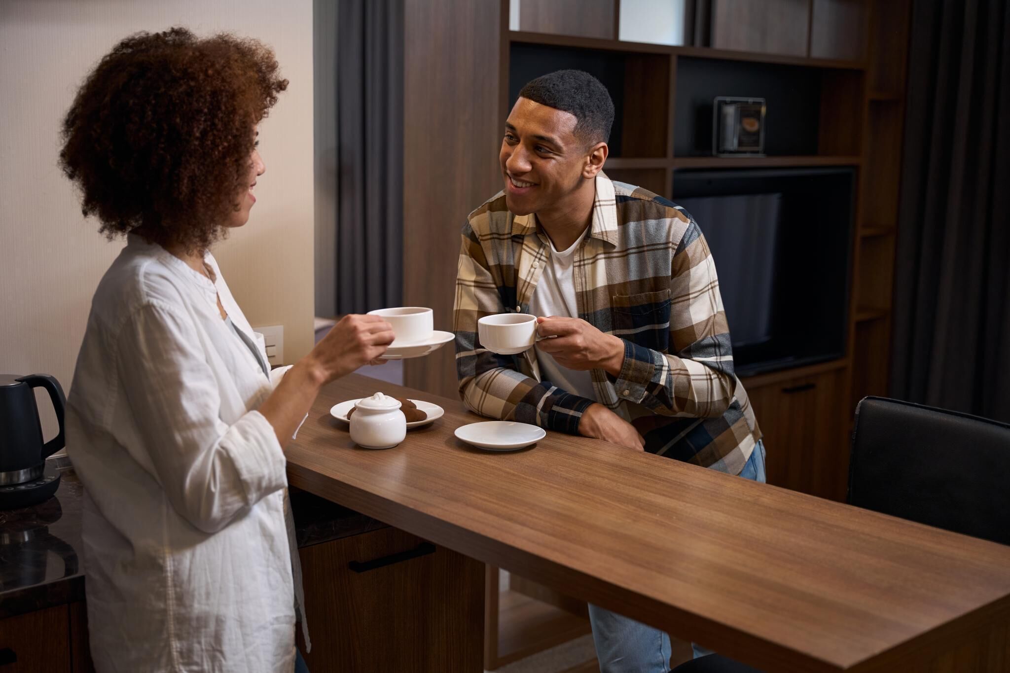 Een moderne keuken met houten aanrecht, een koffiezetapparaat en een eettafel gedekt voor twee personen.